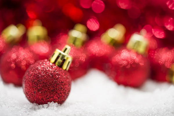 Красные рождественские шары на снегу на фоне красного боке Лицензионные Стоковые Фото