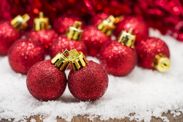 Red Christmas balls on snow against red bokeh background — Stock Photo, Image