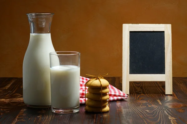 Bodegón de leche de vidrio sobre mesa de madera con galletas — Foto de Stock