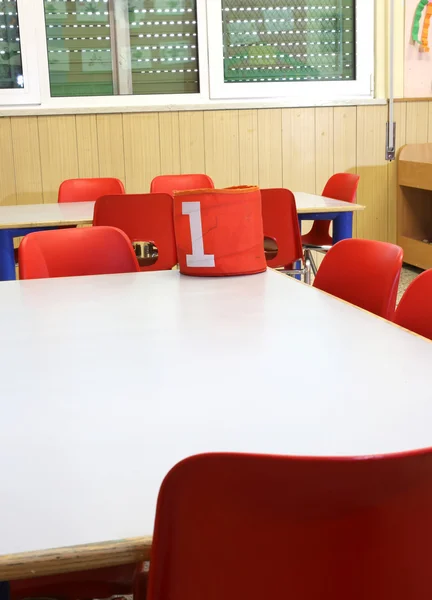 Escritorios y pequeñas sillas rojas dentro de una clase de jardín de infantes —  Fotos de Stock