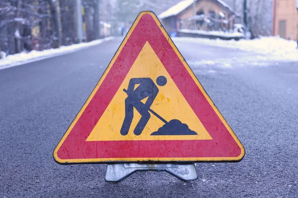 Треугольный дорожный знак работы в процессе на дороге с силуэтом — стоковое фото