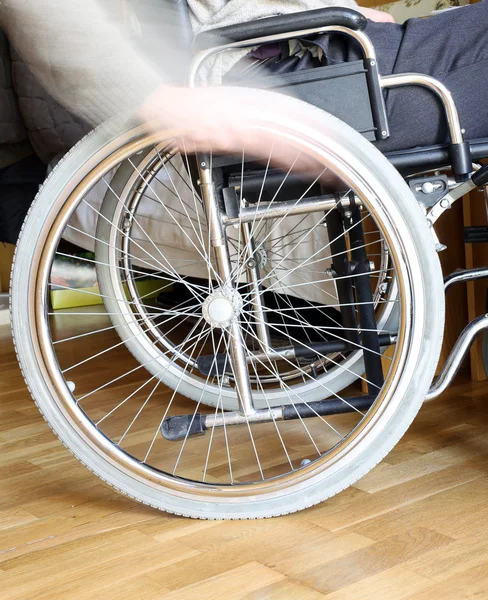 Main du handicapé dans la roue du fauteuil roulant — Photo