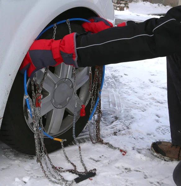 Człowiek z czerwone rękawice zainstalować łańcuchy śniegowe opony samochodu w garniturów źim — Zdjęcie stockowe