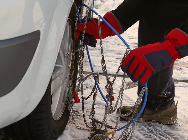 Homem com luvas vermelhas instalar correntes de neve no pneu do carro — Fotografia de Stock