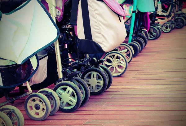 Strollers for toddlers parked on the parquet floor of wood — Stock Photo, Image