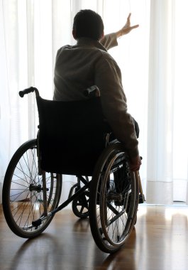 pencerenin yakınındaki odasında tekerlekli sandalyede oturan devre dışı