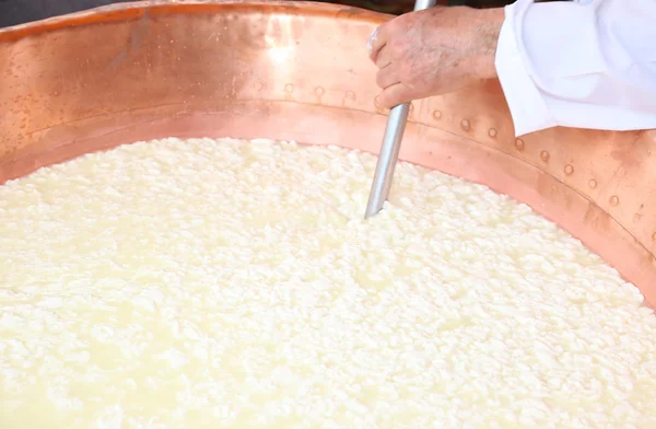 Cheesemaker stirs the curds into the copper cauldron to make che — Stock Photo, Image