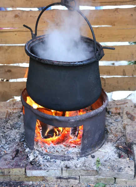 Schwarzer Topf mit angezündetem Feuer und weißem Rauch beim Kochen — Stockfoto