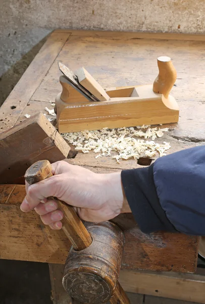 Carpenter's hand in the carpentry workshop with a plane and the — Stock Photo, Image