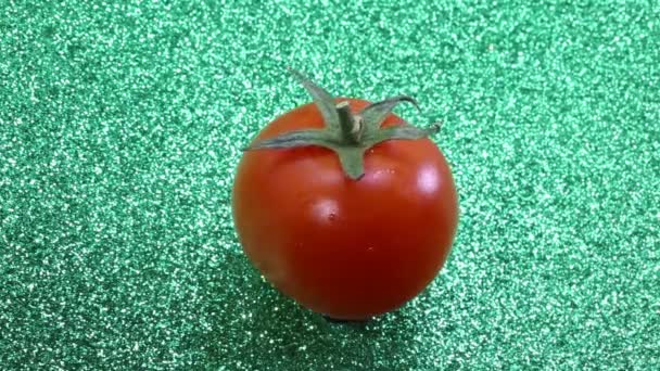 Red tomato rotating in the green glitter background — Stock Video