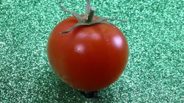 Röd tomat roterande i gröna glitter bakgrunden — Stockvideo