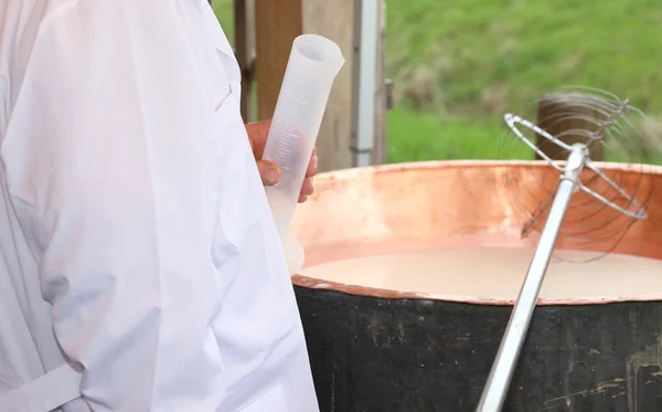 Dairyman with plastic tube to pour the rennet into the milk — Stock Photo, Image