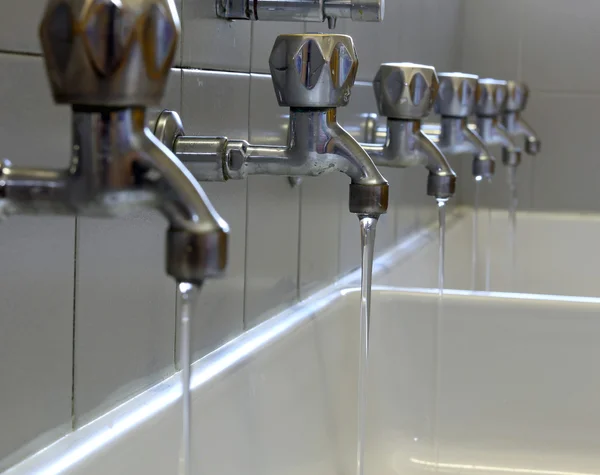 File di rubinetti in acciaio nel bagno degli asili — Foto Stock
