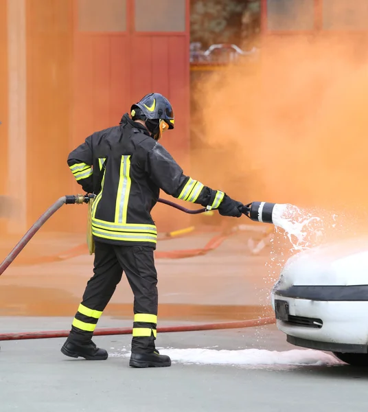 Bomberos durante el ejercicio para apagar un incendio en un coche —  Fotos de Stock