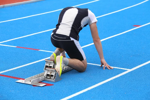 Muskulöser junger Athlet in den Startlöchern eines Leichtathletik-Tracs — Stockfoto