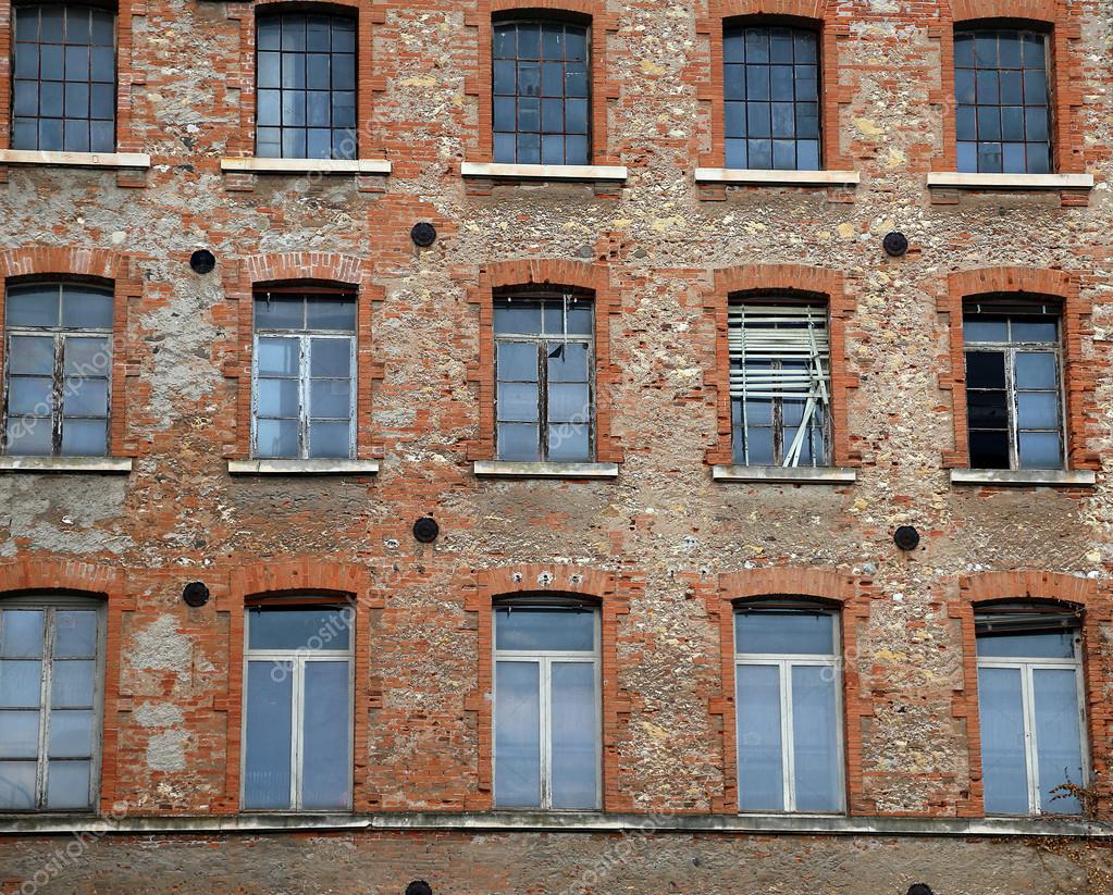 nave industrial con el revestimiento de ladrillos y ventanas rotas