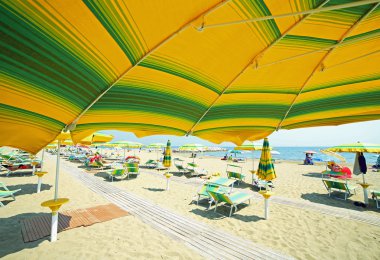 Yaz aylarında güneşli kumsalda sarı şemsiye