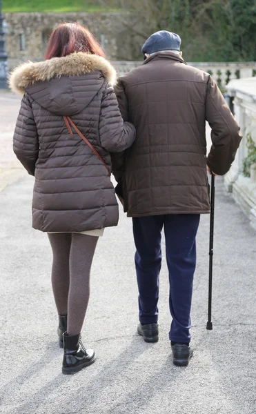 Daughter walk together to the elderly father walking with stick — Stock Photo, Image
