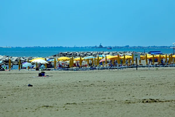 Sunny sandy beach with many tourists 'parasols on holiday by th — стоковое фото