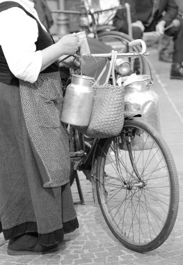 Yaşlı kadın ile bisiklet ve alüminyum süt kutuları