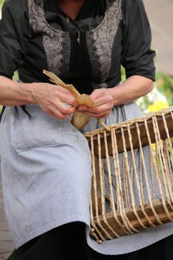 yaşlı bir kadının bir hasır çanta oluşturulurken usta eller