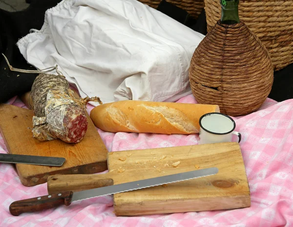 Outdoor picinc with salami, bread and big knife and flask — Stock Photo, Image