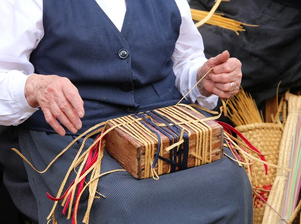 Пожилая женщина при создании соломенной сумки — стоковое фото