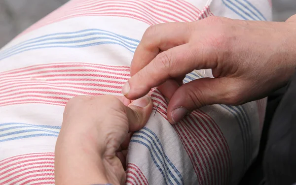 Händerna på gammal kvinna medan du syr med nål och tråd — Stockfoto