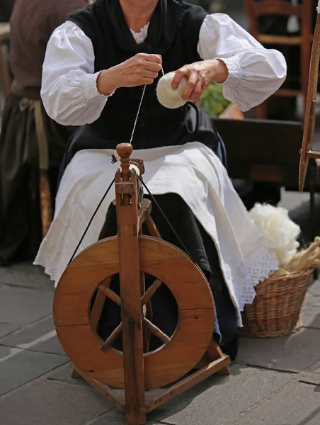 Mulher com roda de fiação de madeira enquanto gira um fio — Fotografia de Stock