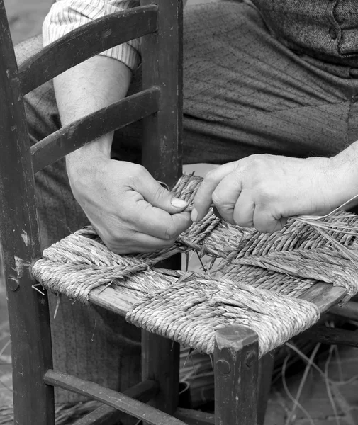 Mender of chairs while repairing an old chair with straw — Stock Photo, Image