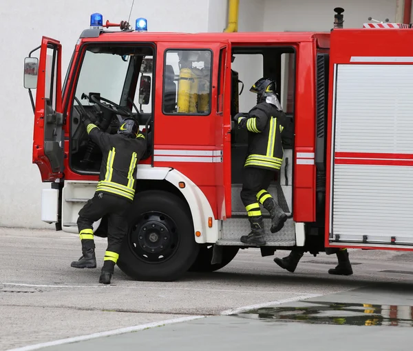 Motor de bombeiros transportando dois bombeiros para combater o fogo — Fotografia de Stock