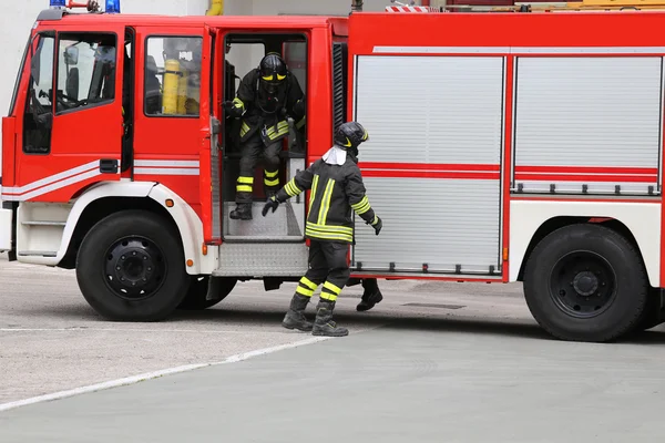 Červené hasičské auto zastavil hořící budovy. — Stock fotografie