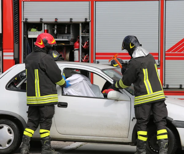 Pompiers tout en sauvant les blessés dans la voiture cassée — Photo