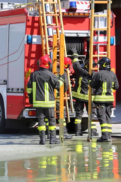 Firefighters in action take the ladder from the fire engine — Stock Photo, Image