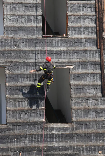 Escaladores de bombeiros escalando uma parede de uma casa durante o f — Fotografia de Stock