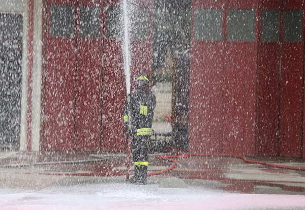 Хоробрий пожежник під час пожежної дрилі з піною шланга — стокове фото