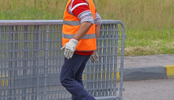 Worker with reflective jacket moves iron hurdles — Stock Photo, Image