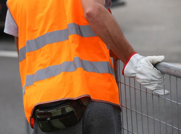 Young worker with gloves moves iron hurdles on the road — Stock Photo, Image