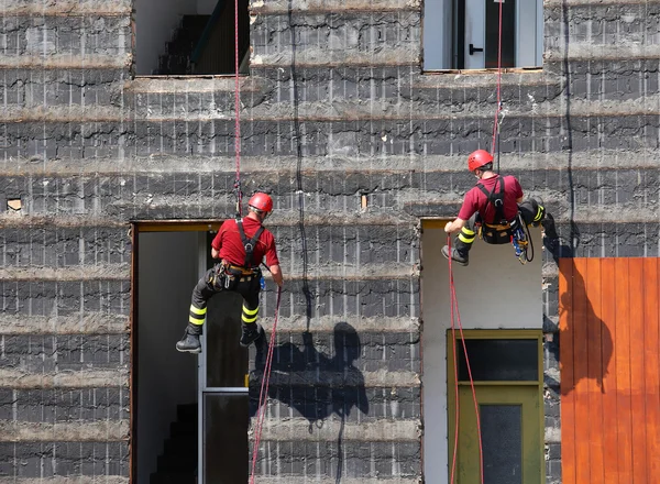 Escaladores de bomberos escalando una pared de una casa durante la f — Foto de Stock