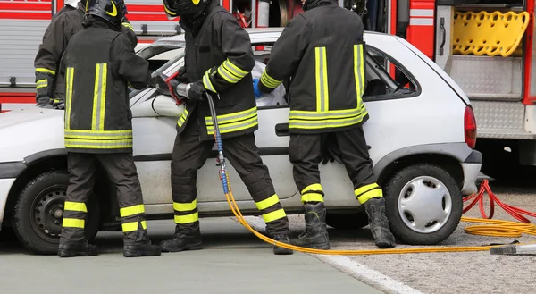 Moedige brandweerlieden verlichten een gewonde na een auto-ongeluk — Stockfoto