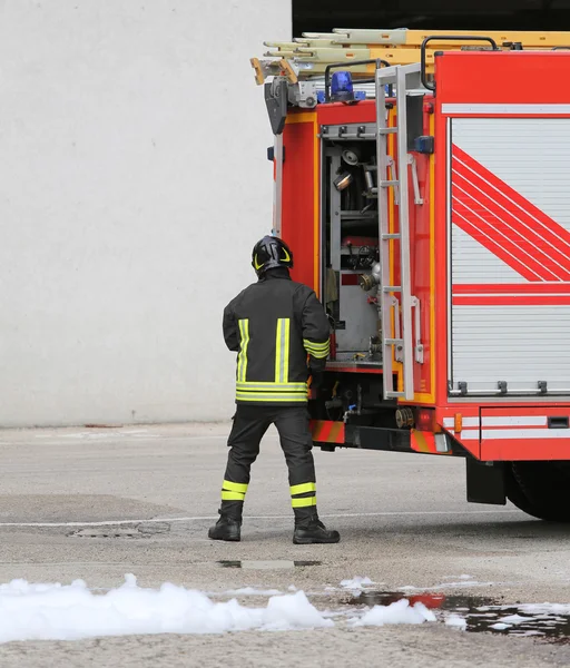 Bombeiro em uniforme de prevenção de incêndio e caminhão de bombeiros — Fotografia de Stock