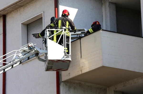 Два пожарных в повышенной клетке пожарной машины — стоковое фото