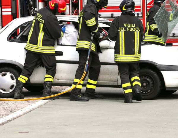 Coraggiosi vigili del fuoco alleviare un ferito dopo un incidente stradale — Foto Stock