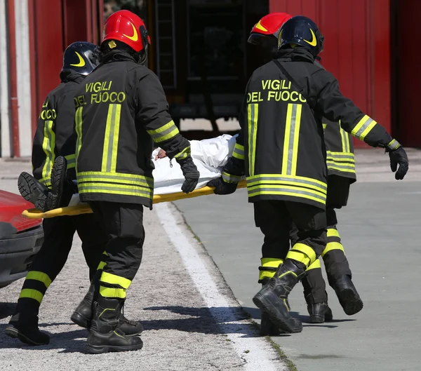 Italian firefighters in action carry a stretcher with injured af — Stock Photo, Image