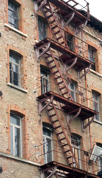 Zchátralé průmyslové budovy s rezavou požárním schodišti s faci — Stock fotografie