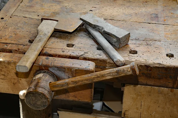 Sekera a velké kladivo na starý dřevěný pracovní stůl s svěrák — Stock fotografie