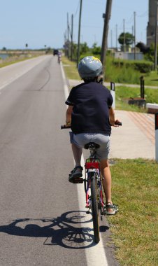 Yol boyunca koruyucu kask ile bir bisiklet sürme çocuk