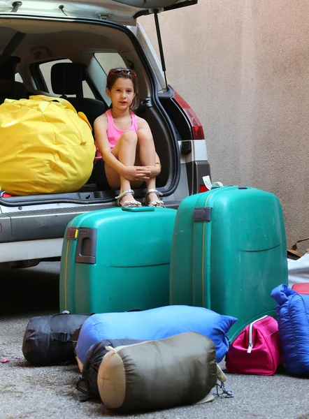 Маленька дівчинка завантажує машину під час літніх канікул — стокове фото
