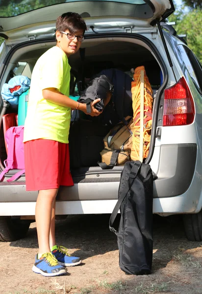 眼鏡の少年が車のトランク内の荷物を読み込みます — ストック写真