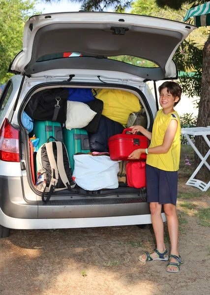 Giovane ragazzo carica i bagagli nel bagagliaio della sua auto — Foto Stock